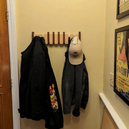 Holz-Wandgarderobe mit Jacken und Baseballkappe, platzsparend, Flur, modern, beige Wand.