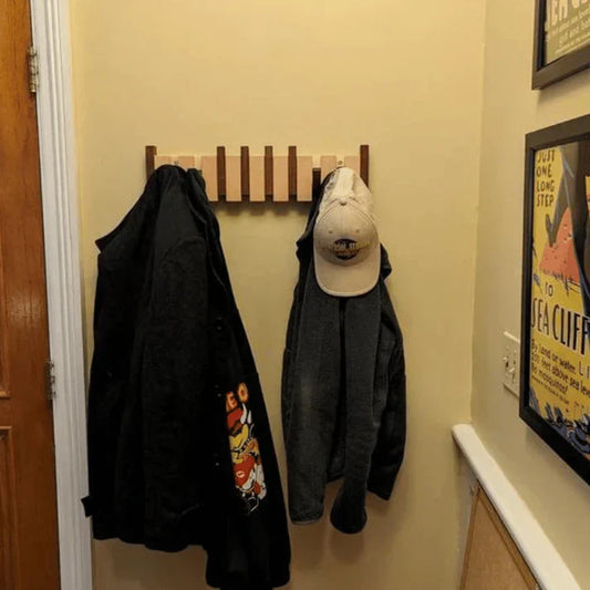Holz-Wandgarderobe mit Jacken und Baseballkappe, platzsparend, Flur, modern, beige Wand.