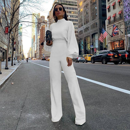 Frau in weißem Jumpsuit mit Stehkragen auf Stadtstraße, modisch, elegant, urbaner Stil.