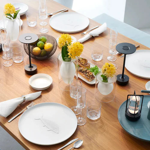 Eleganter Esstisch mit gelben Blumen, modernen Lampen und Geschirr, ideal für Restaurantdekoration.