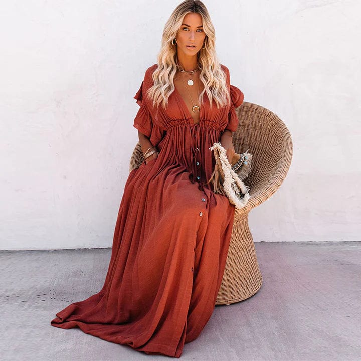 Frau in rotem, langem Kleid aus Leinen, sitzt auf Rattanstuhl, Sommermode, Boho-Stil.