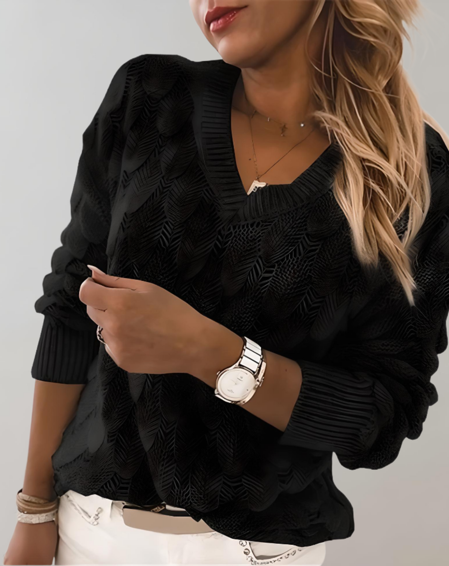 Frau in schwarzem Strickpullover, V-Ausschnitt, Armbanduhr, blonde Haare, modisch, elegant.