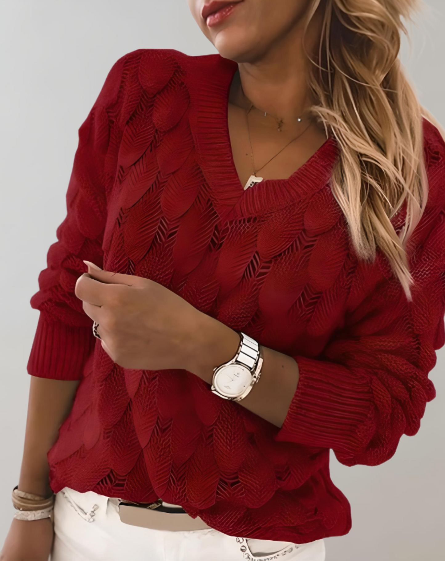 Frau in rotem Strickpullover, V-Ausschnitt, Armbanduhr, blonde Haare, modisch, elegant.