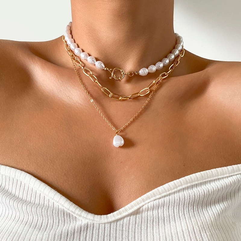 Frau trägt Perlen- und Goldketten-Set, eleganter Schmuck, modisches Accessoire.