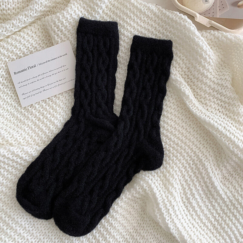 Schwarze Stricksocken auf weißer Decke, warme Wintermode, gemütliche Accessoires.
