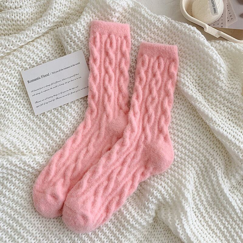 Rosa gestrickte Socken auf weißem Strickhintergrund, weiche warme Winterbekleidung.