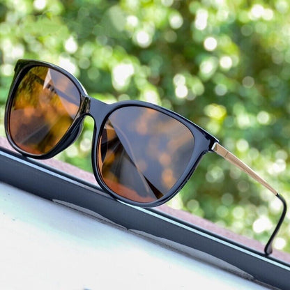 Schwarze Sonnenbrille mit braunen Gläsern auf Fensterbank, modisches Accessoire, UV-Schutz.