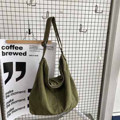 Grüne Canvas-Umhängetasche auf Gitterhintergrund, modisch und geräumig.