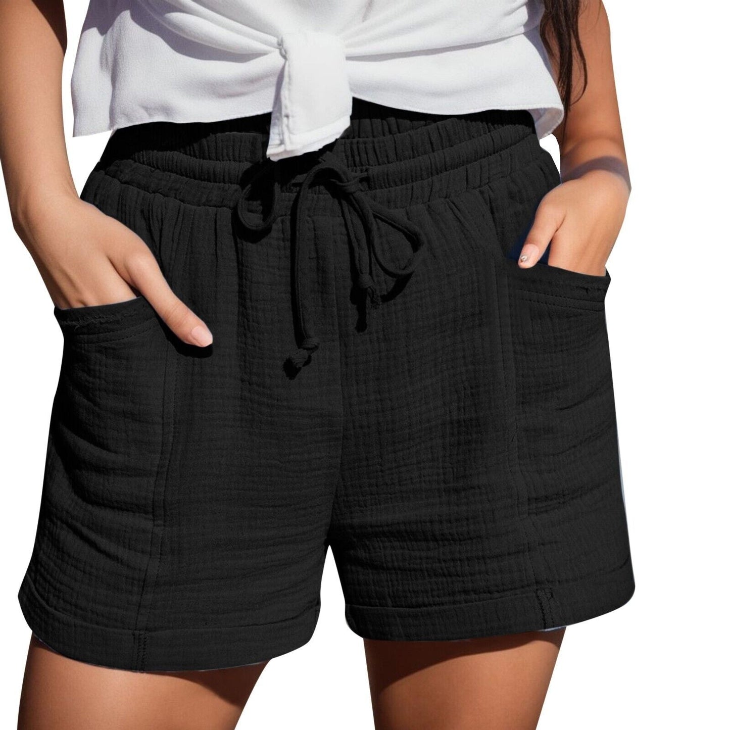 Frau in schwarzer Baumwollshorts mit Taschen und weißem Oberteil, Sommermode.
