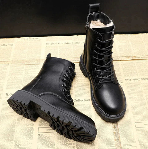Schwarze Lederstiefel mit Fellfutter, robuste Sohle, Schnürung, Reißverschluss, auf Zeitung.