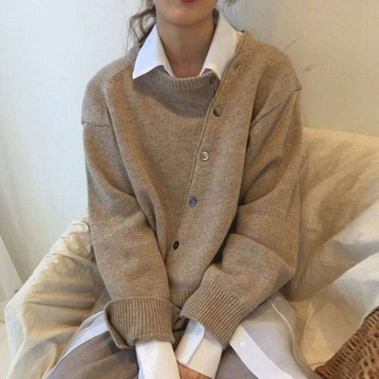 Frau trägt beigen Kaschmir-Cardigan mit Knopfleiste, über weißer Bluse, gemütlicher Look.