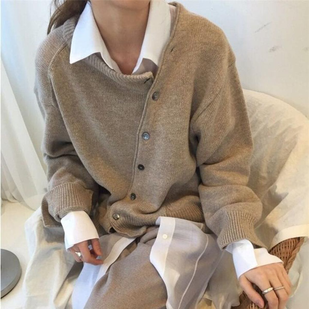 Frau trägt beigen Kaschmir-Cardigan mit Knöpfen, über weißer Bluse, gemütlicher Herbstlook.