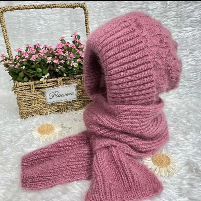 Rosa Strickmütze und Schal aus Wolle, dekoriert mit Blumen, auf weißem Hintergrund.