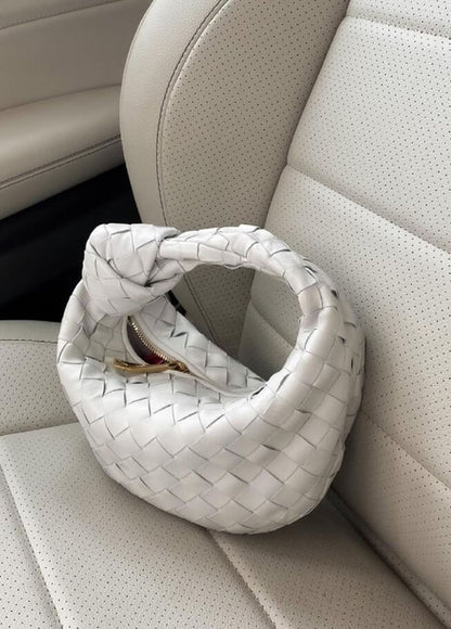 Weiße geflochtene Handtasche aus Leder auf Autositz, modisches Accessoire, Damenmode.
