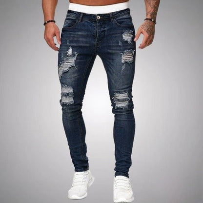Man i mörkblå slitna slim fit-jeans med revor på lår och knän, framifrån, med vita sneakers. 4