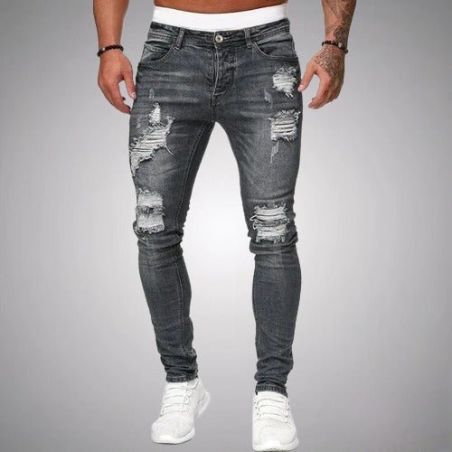 Man i gråa slitna slim fit-jeans med revor på lår och knän, framifrån, med vita sneakers. 5