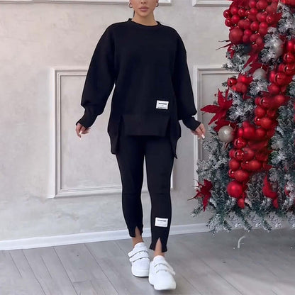 Frau in schwarzem Oversize-Pullover und Leggings, weiße Sneaker, neben Weihnachtsbaum.
