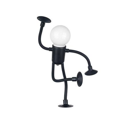 Svart lampfigur står på ett ben med sugpropp, ena armen lyft och det andra benet böjt, mot vit bakgrund. 15