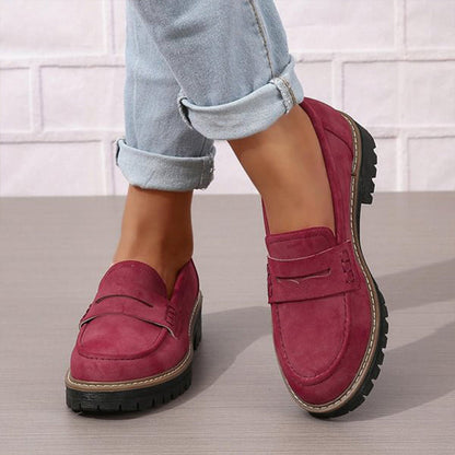 Vinröda loafers med grov svart sula, burna med uppvikta ljusblå jeans, sedda snett framifrån. 4