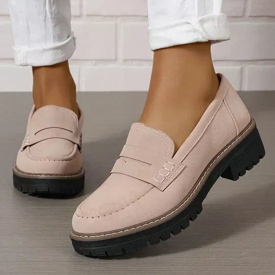 Ljust rosabeiga loafers med tjock svart sula, burna med uppvikta vita jeans mot tegelvägg. 8
