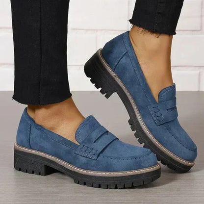 Blå loafers med kraftig svart sula och beige kant, burna med svarta byxor med fransad fåll. 9
