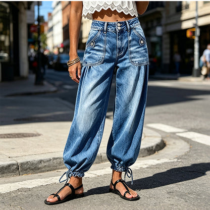 Modell i blå jeans med hög midja och knytband vid fållen, fotograferad på en solig stadsgata. 2