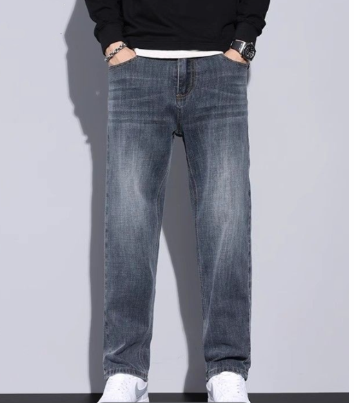 Blågrå jeans med slitna veck, burna med svart tröja och vit sneaker, båda händerna i fickorna. 11