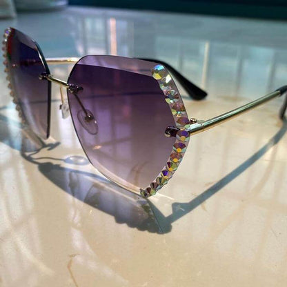 Luxuriöse Sonnenbrille mit lila Gläsern und funkelndem Strassrand auf Marmortisch.