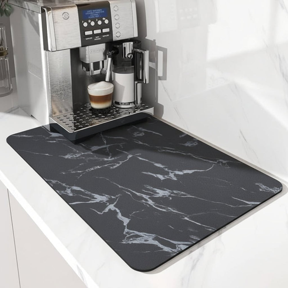 Svart matta med vita marmoråderor under en kaffemaskin på en vit marmorbänk, fotograferad från vänster sida. 4