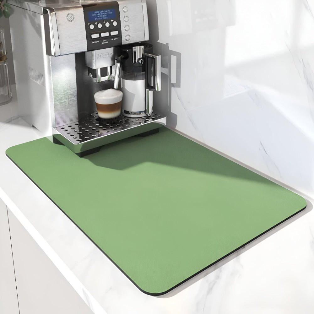 Ljusgrön matta med rundade hörn framför en kaffemaskin på en vit marmorbänk, närbild på maskinens frontpanel. 6