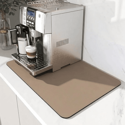 Beige matta under en silverfärgad kaffemaskin på en vit bänk, med en latte på droppgallret. 7