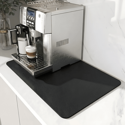 Svart matta med lätt texturerad yta under en silverfärgad kaffemaskin på en vit marmorbänk. 9