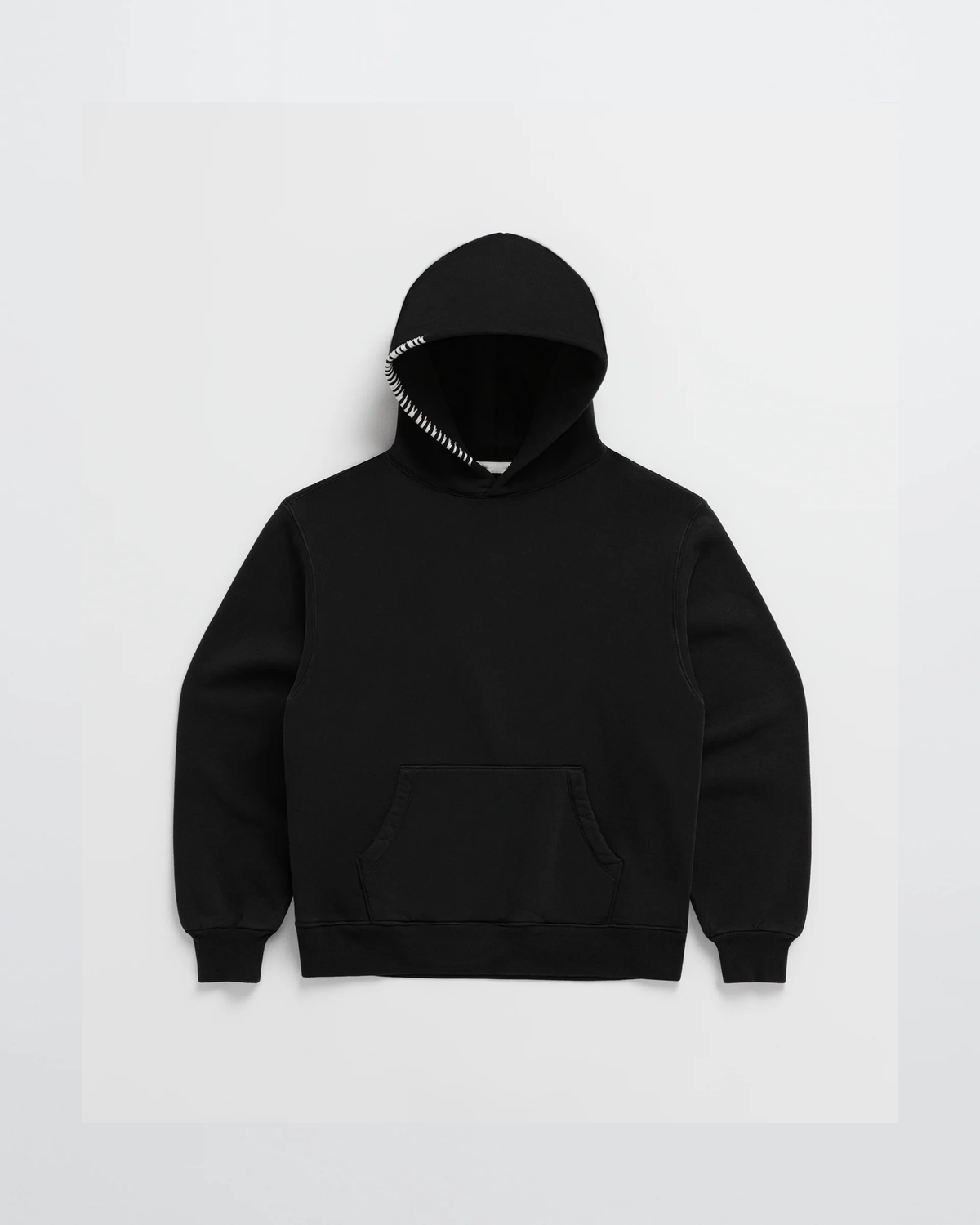 Svart hoodie sedd framifrån, med känguruficka och kontrasterande vit dekorsöm längs ena huvkanten. 5