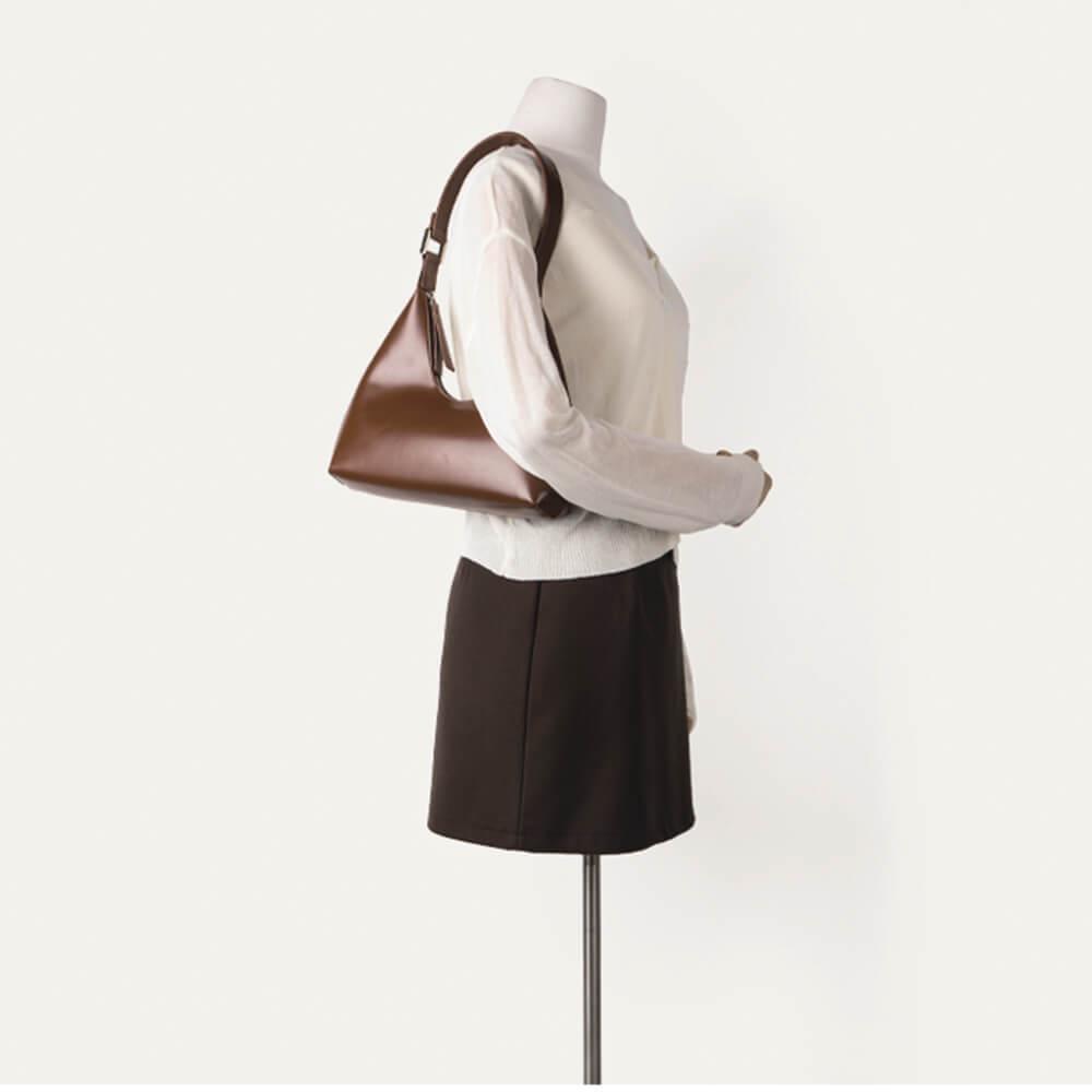 Braune, tragbare Halbmondtasche aus Leder auf Schaufensterpuppe, modisch und elegant.
