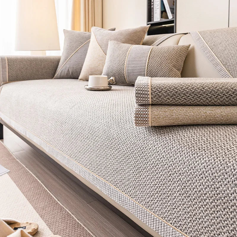 Soffa med gråbeige överdrag och två hopvikta överdrag i grått och sand liggande på sittytan. 6