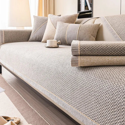 Soffa med gråbeige överdrag och två hopvikta överdrag i grått och sand liggande på sittytan. 6