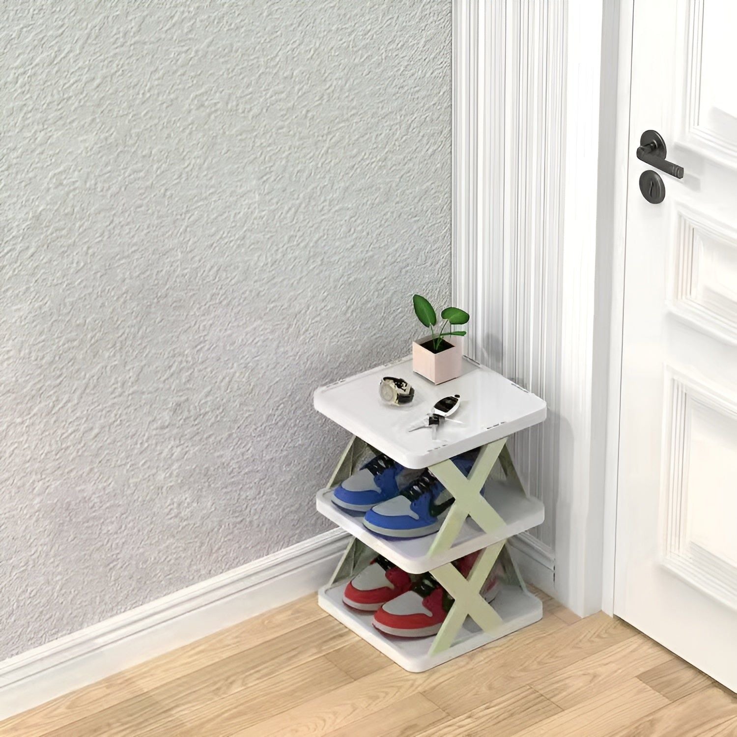 Weißes faltbares Schuhregal mit drei Ebenen, platzsparend, mit Schuhen und Pflanze, in Ecke.
