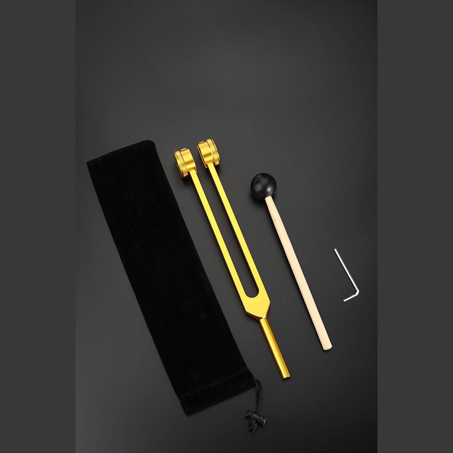 Goldene Stimmgabel mit schwarzem Beutel und Klöppel auf schwarzem Hintergrund.