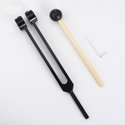 Schwarzes Stimmgabel-Set mit Holzklöppel und Inbusschlüssel auf weißem Hintergrund.