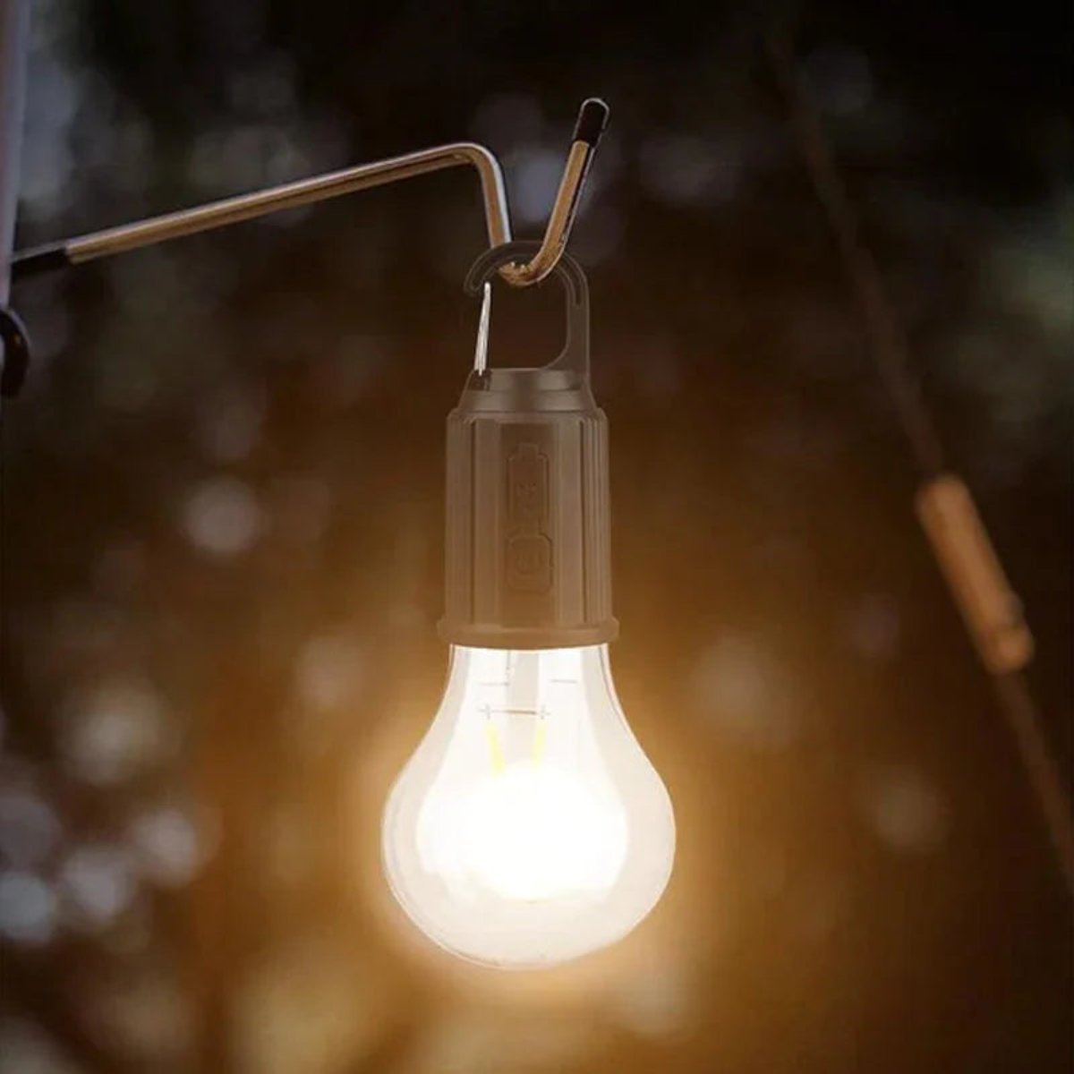 Tänd lampa hängd med karbinhake på en metallkrok, mjuk varm glöd i kvällsmörkret 4