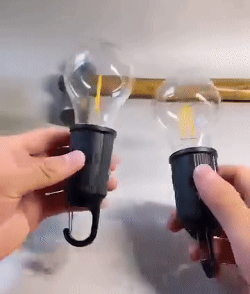 Två händer håller varsin lampa med glödtråd och krok mot en ljus vägg 6