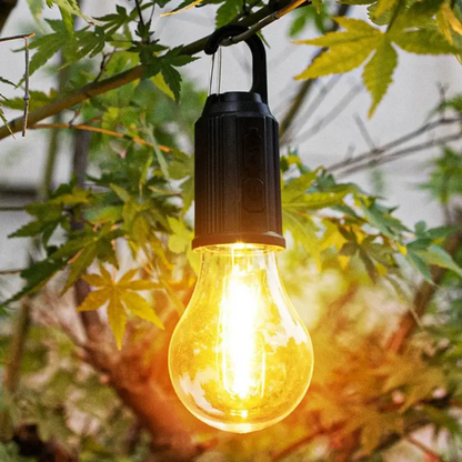 Tänd lampa hängd på en trädgren bland gröna löv, med knappar på sidan 8