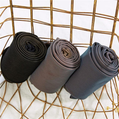 Drei Paar extra warme Leggings, schwarz, grau, blau, auf einem goldenen Drahtkorb.
