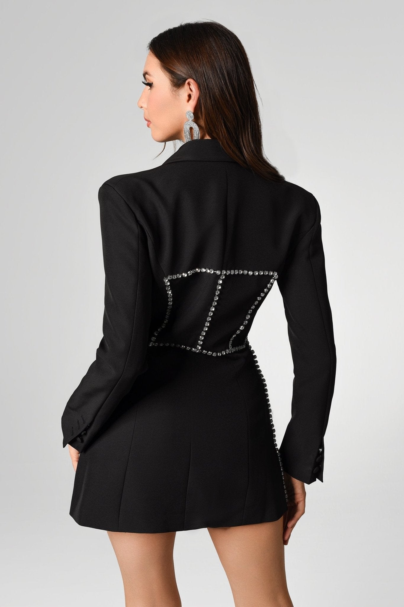 Frau in schwarzem, zweireihigem Karo-Blazer mit langen Ärmeln und Schmuckdetails.