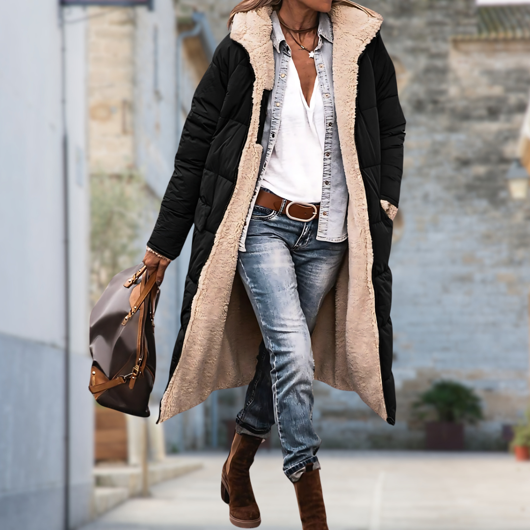 Svart lång quiltad jacka med beige teddyfoder, öppen och buren av modell på gatan med jeans, boots och handväska. 4