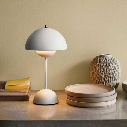 Weiße Tischlampe auf Tisch mit Holztabletts und dekorativer Vase, modernes Innendesign.