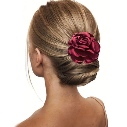 Frau mit eleganter Hochsteckfrisur und roter Rosen-Haarspange aus Satin.
