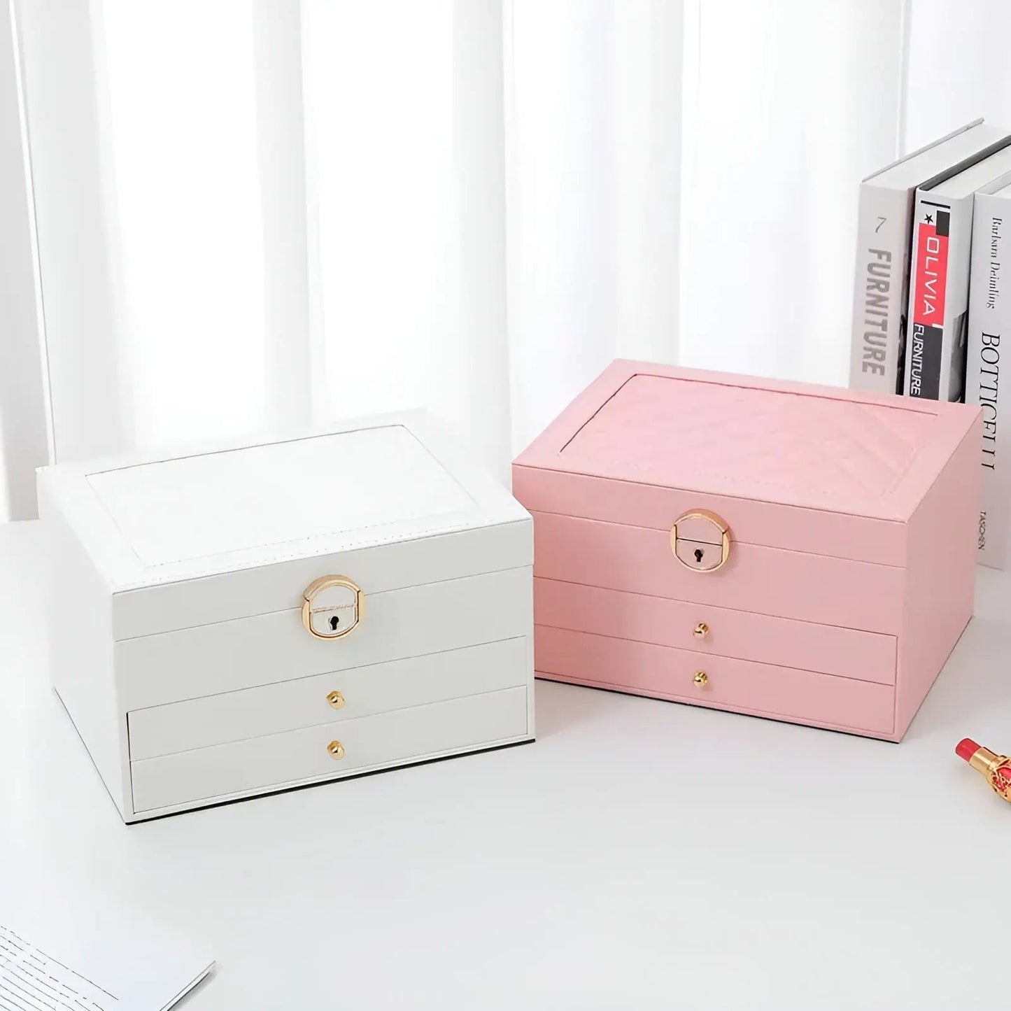 Zwei Schmuckkästchen, weiß und rosa, mit Schubladen und goldenen Griffen auf weißem Hintergrund.