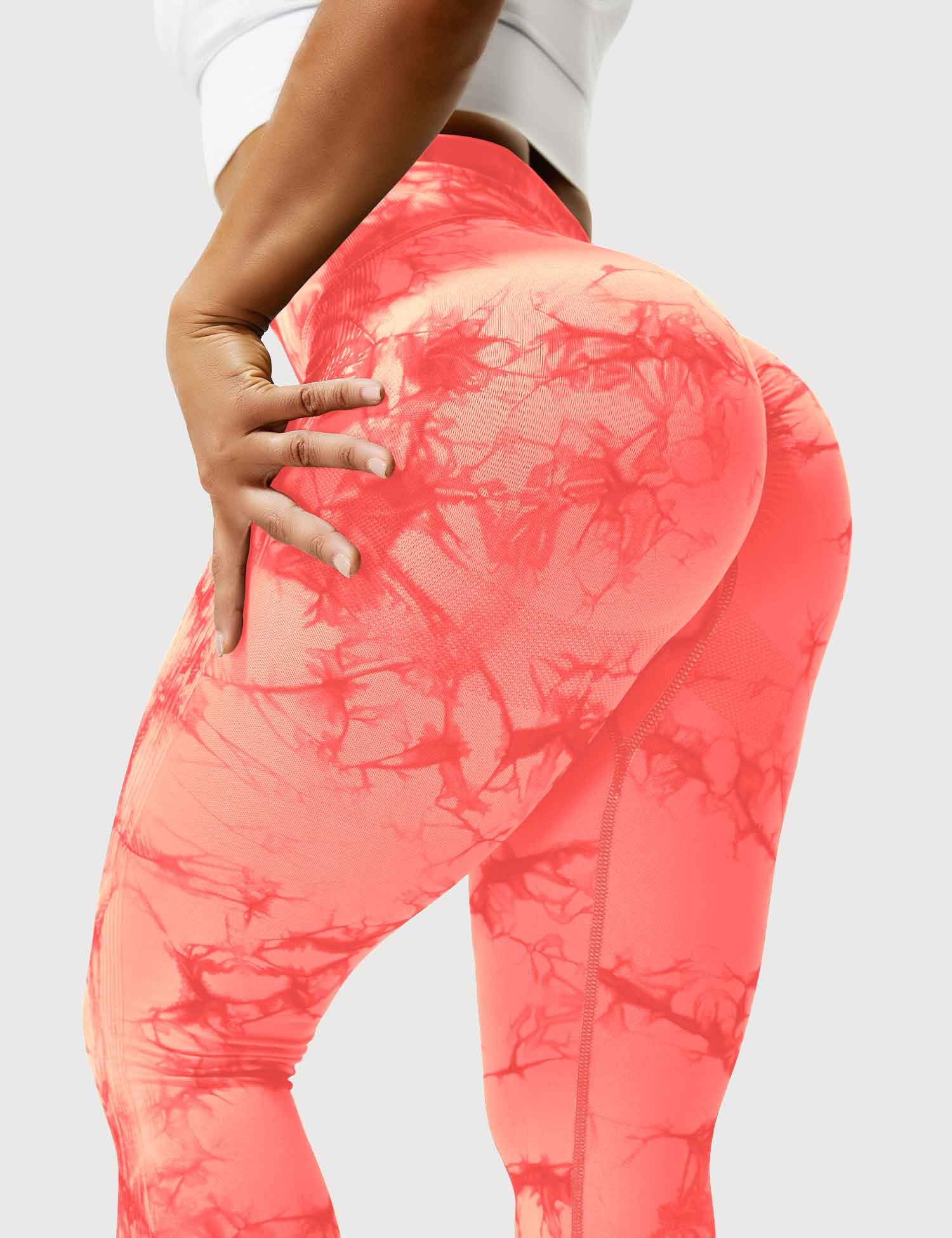 Frau in orangefarbenen Leggings mit Marmormuster, Sportbekleidung, Fitnessmode, elastisch.
