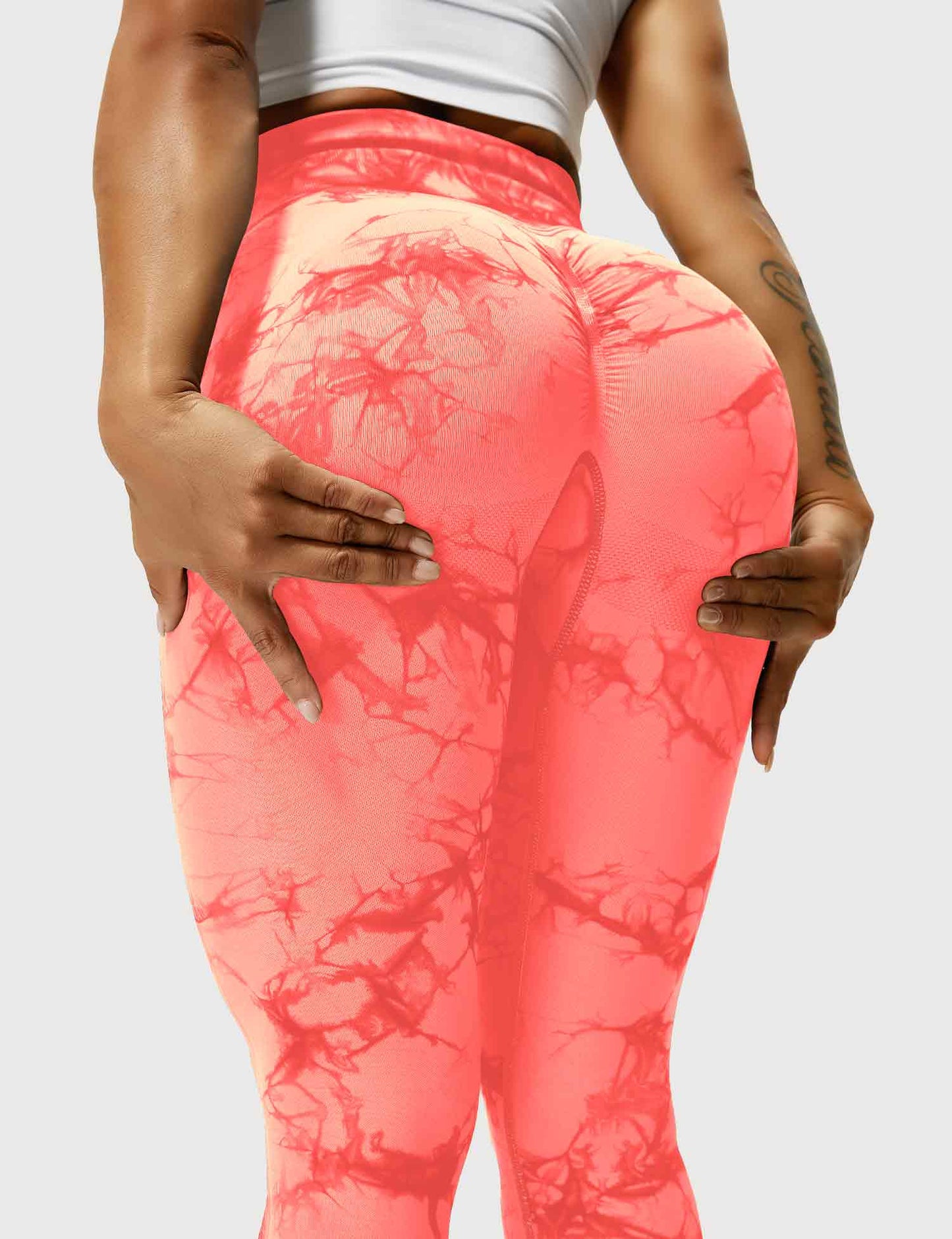 Frau in orangefarbenen Leggings mit Marmormuster, Sportbekleidung, Fitnessmode.